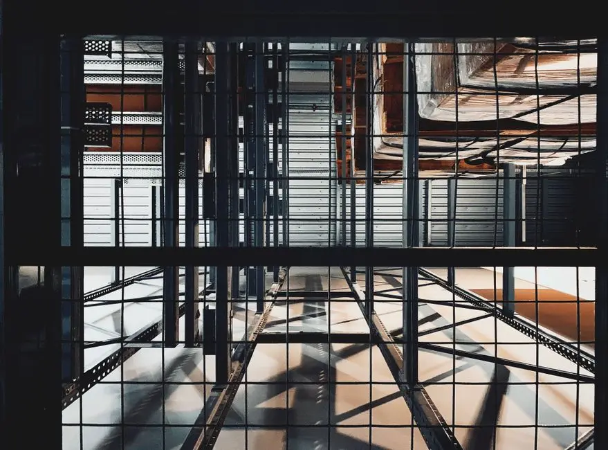 Inside view of a complex industrial metal structure with shadows casting through scaffolding and steel beams.